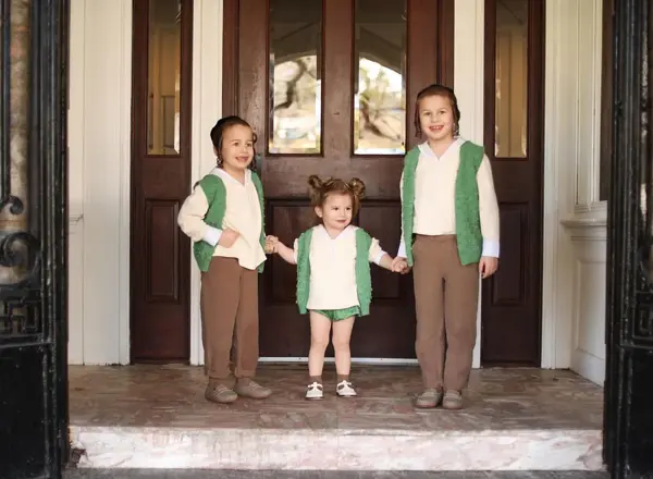 Three siblings in green vests by tall wooden doors, studio photography by Photoholic, Monsey NY