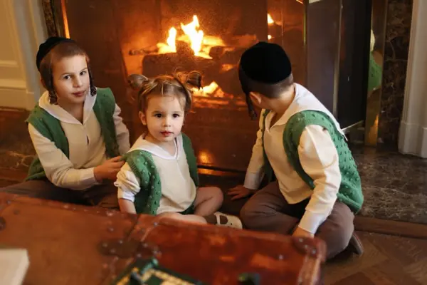 Three siblings by a crackling fireplace, studio photography by Photoholic, Monsey NY