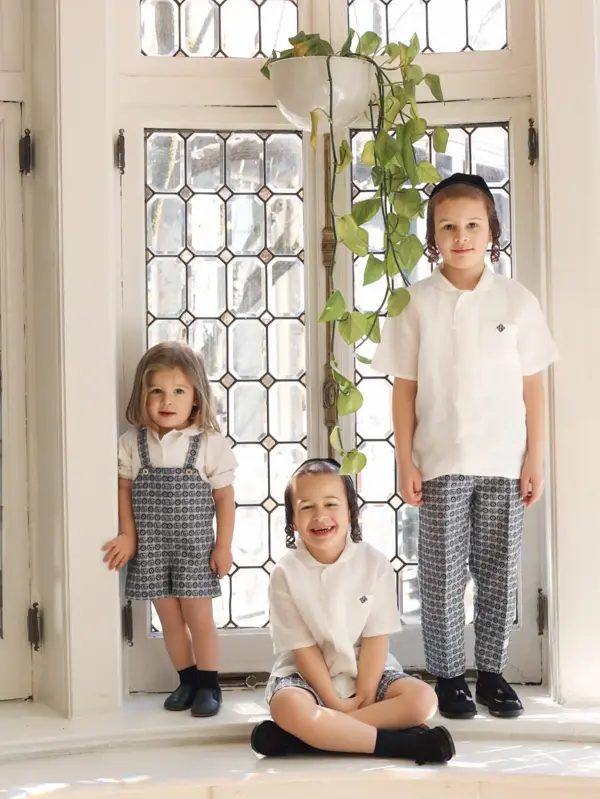 Three siblings posing by an arched window with greenery, studio photography by Photoholic, Monsey NY