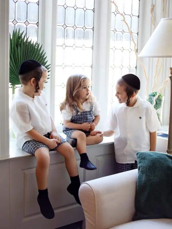 Three siblings sitting together on a window seat, studio photography by Photoholic, Monsey NY