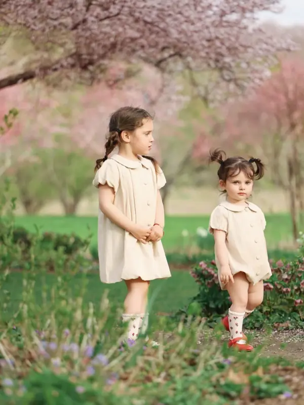 Two sisters in cream dresses under pink blossom trees, outdoor photography by Photoholic, Rockland County NY